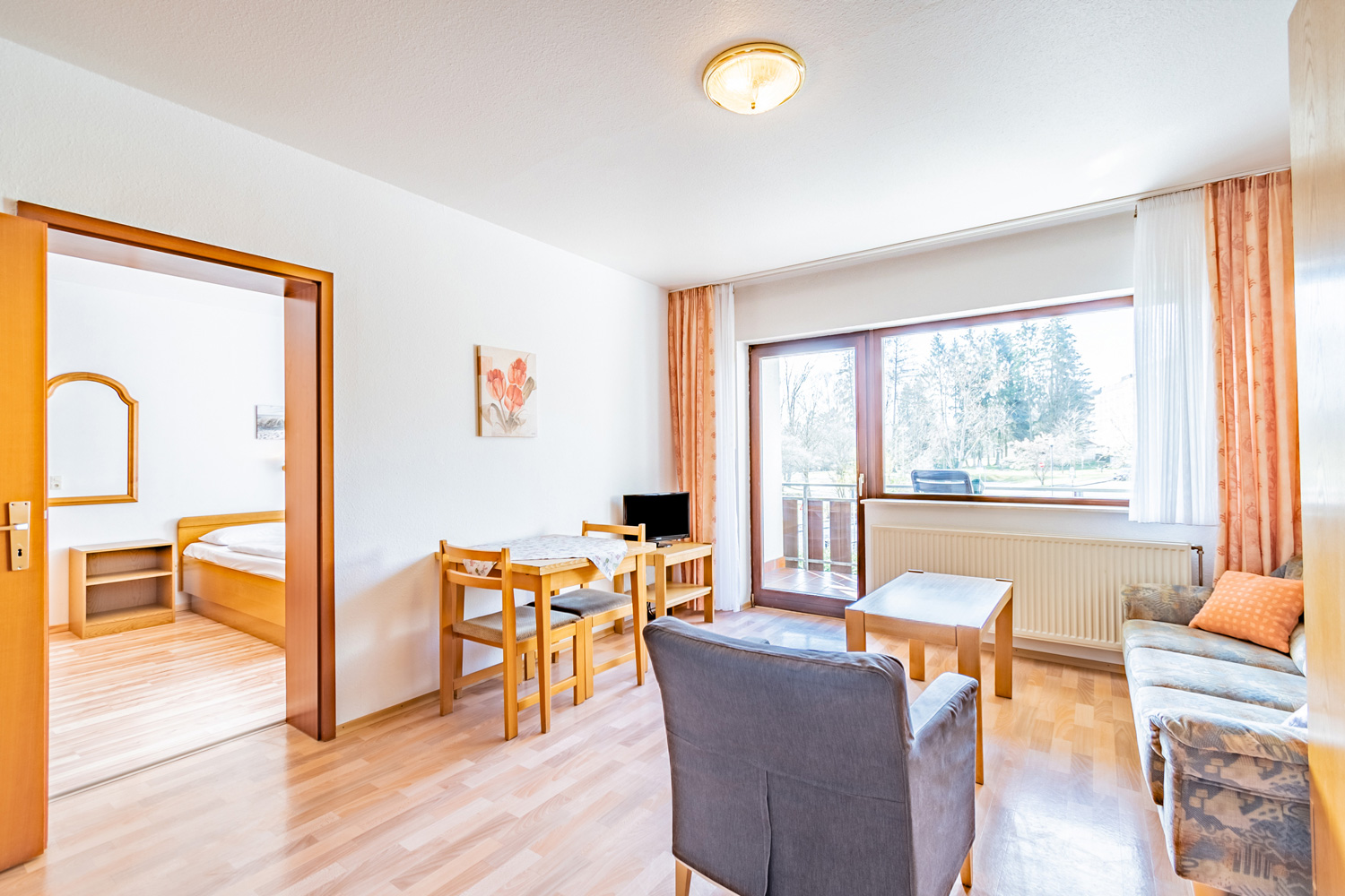 Hotel room with sofas, a TV, and an adjacent bedroom